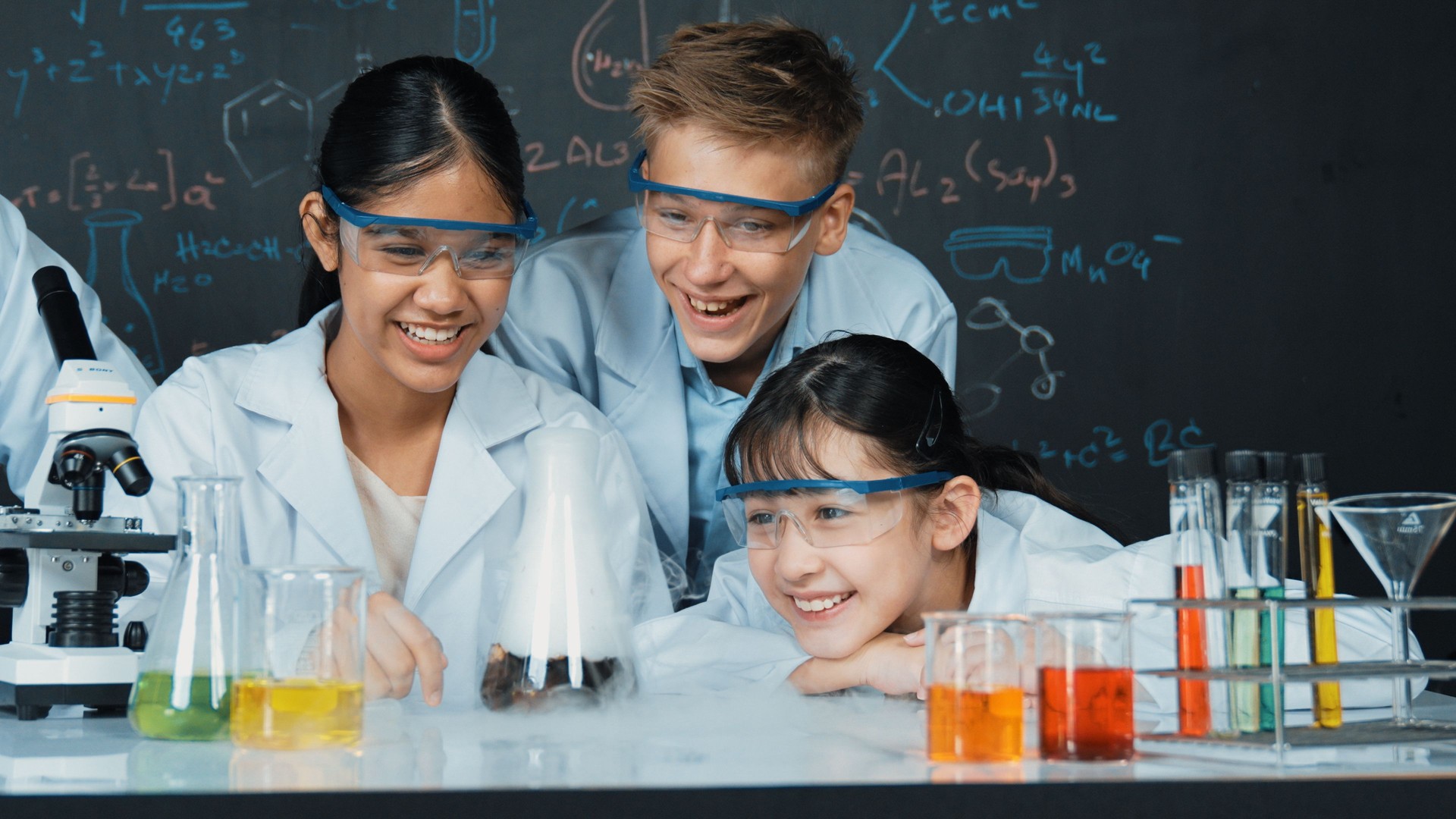Cute girl looking at beaker while doing experiment in STEM class. Edification.