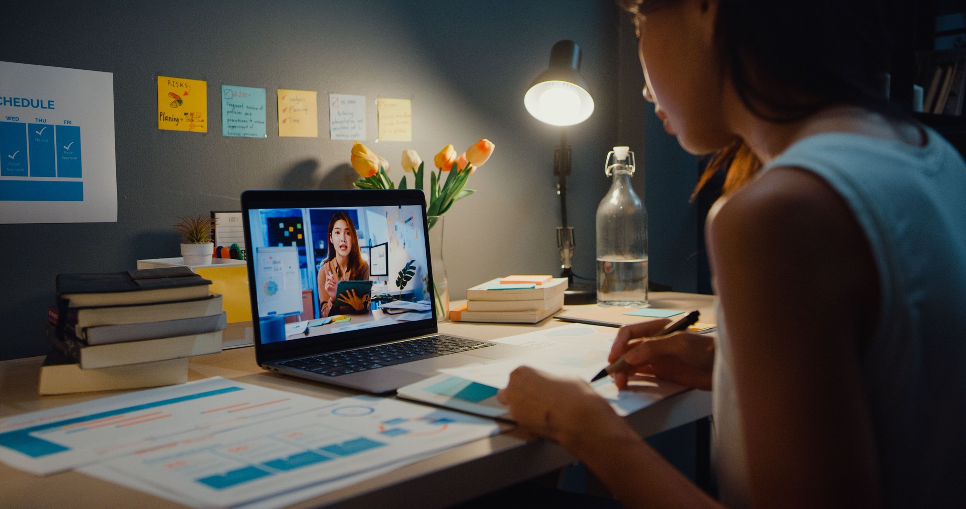 Asia businesswoman using laptop talk to colleagues about plan in video call meeting at living room at home.